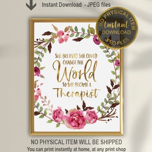May include: A framed print with the text "She Believed She Could Change the World So She Became a Therapist." The text is in gold script, surrounded by a floral wreath with pink and burgundy flowers. The frame is gold.