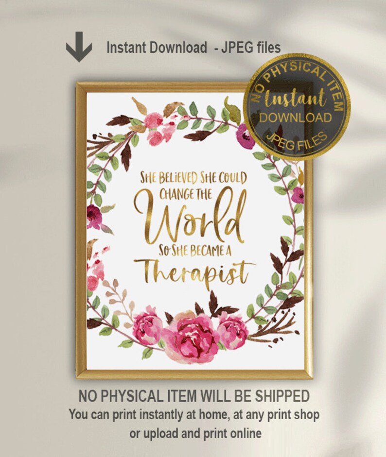 May include: A framed print with the text "She Believed She Could Change the World So She Became a Therapist." The text is in gold script, surrounded by a floral wreath with pink and burgundy flowers. The frame is gold.