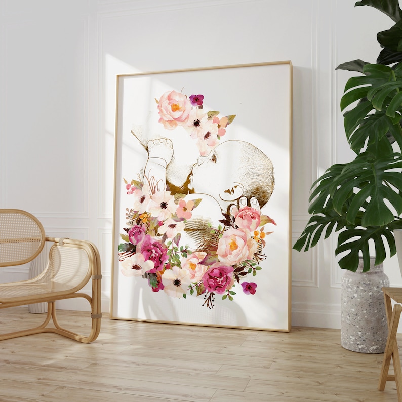 May include: A gold outline of a baby in a fetal position surrounded by a wreath of pink, white, and purple flowers.