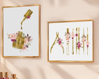 May include: Two framed wall art prints with gold frames. The left print shows a gold nail polish bottle with floral accents. The right print displays a collection of gold manicure tools, including nippers and pushers, decorated with pink and purple flowers.