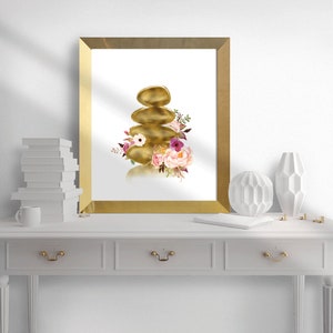 May include: A gold-toned zen stone stack with pink and purple flowers, a watercolor illustration in a gold frame.