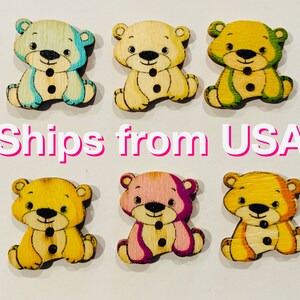 May include: Six wooden bear buttons with different colored designs. The bears are all sitting down with their paws in front of them. The colors include blue, yellow, green, pink, and orange.