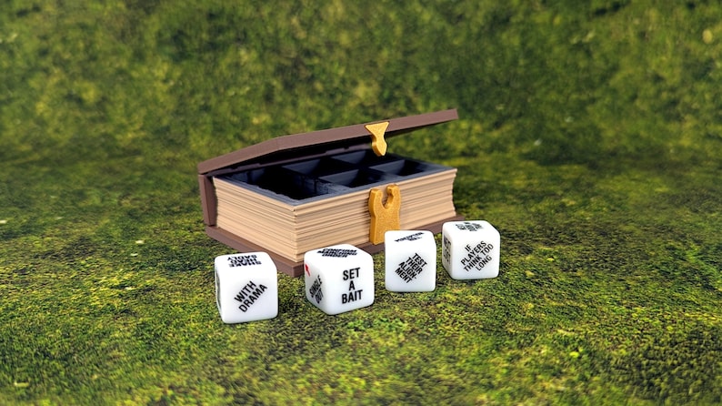 May include: A brown wooden box with a book-like design, open to reveal compartments. Four white dice with black text are in front of the box. The dice read "WITH DRAMA", "SET A BAIT", "TEST YOUR MIGHT", and "IF PLAYERS THINK TOO LONG".