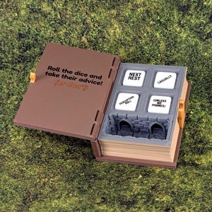May include: A brown, open book-shaped dice box with a gray interior. The box contains four white dice with phrases like "Next Rest" and "Casually." The cover reads "Roll the dice and take their advice! (or don't)." The background is green.