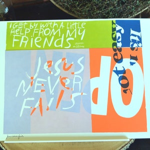 May include: A colorful art print with the words "I get by with a little help from my friends" and "Jesus never fails." The design features bold typography in white, orange, blue, and green against a white background.