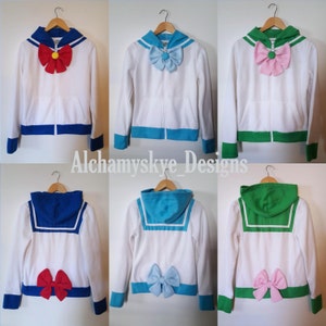 May include: Six white zip-up hoodies with different colored sailor collars and bows. The collars are blue, green, and turquoise. The bows are red, pink, light blue, and green.