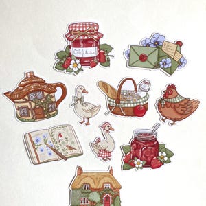 May include: A selection of charming stickers depicting a cottage, goose, chicken, jam jars, picnic basket, and an open book. The stickers have a hand-drawn aesthetic with a gentle colour scheme, ideal for crafting or embellishing.
