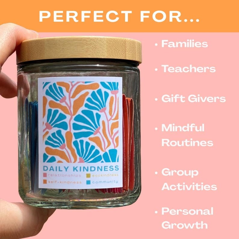 May include: A glass jar with a wooden lid filled with colorful paper strips. The jar has a label that says "Daily Kindness" with the words "relationships, self-kindness, eco-kindness, community" printed below.