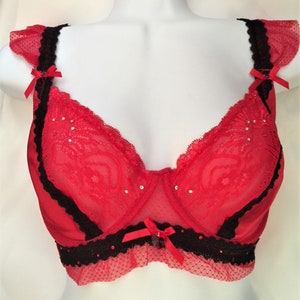 May include: Red lace bra with black trim and rhinestones. The bra has adjustable straps and a hook and eye closure in the back.