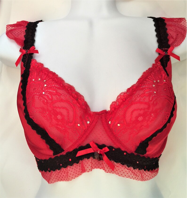 May include: Red lace bra with black trim and rhinestones. The bra has adjustable straps and a hook and eye closure in the back.
