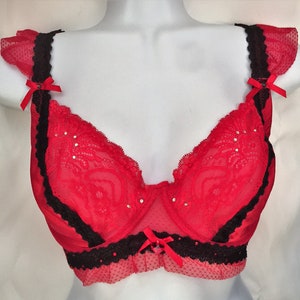 May include: Red lace bra with black trim and rhinestones. The bra has adjustable straps and a hook and eye closure in the back.