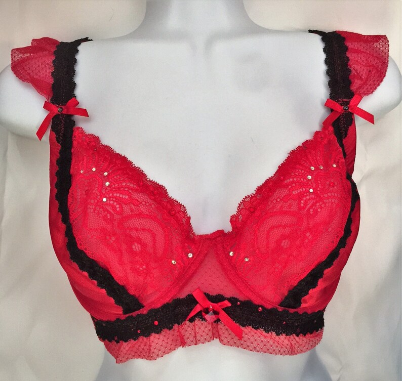 May include: Red lace bra with black trim and rhinestones. The bra has adjustable straps and a hook and eye closure in the back.