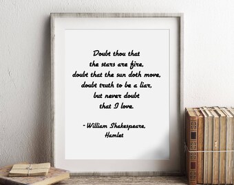 May include: A framed print with a black and white quote from William Shakespeare's Hamlet. The quote reads "Doubt thou that the stars are fire, doubt that the sun doth move, doubt truth to be a liar, but never doubt that I love." The print is sitting on a wooden shelf with a stack of books and a clock.