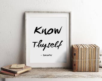 May include: A framed print with the quote "Know Thyself - Socrates" on a white background. The print is on a wooden shelf with a stack of books and a clock.