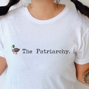 May include: White t-shirt with a graphic of a duck and the text "The Patriarchy."