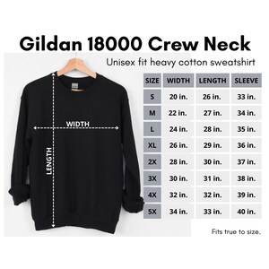 Puede incluir: Una sudadera de cuello redondo negra Gildan 18000 con una tabla de tallas que muestra las medidas en pulgadas para el ancho, la longitud y la longitud de la manga. La tabla incluye las tallas S, M, L, XL, 2X, 3X, 4X y 5X.