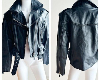 May include: A black leather motorcycle jacket with a zipper closure, a belt at the waist, and a zippered pocket on the left sleeve.