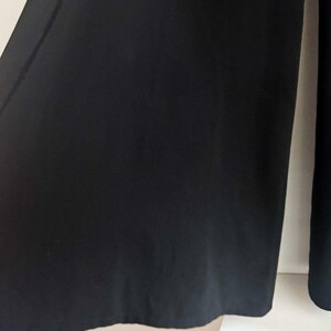 May include: A pair of solid black wide-leg trousers featuring a clean, unadorned design with a straight hemline. The fabric appears smooth and opaque, falling in a relaxed silhouette that extends from the waist down to the lower leg area.