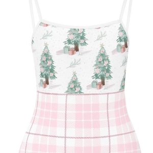 Pode incluir: Um fato de banho de uma peça com um design natalino. A parte superior apresenta um padrão de árvores de Natal com decorações rosa e presentes, enquanto a parte inferior tem um padrão xadrez rosa e branco. Possui finas alças brancas.