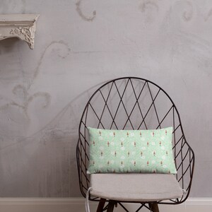 May include: A green and white patterned throw pillow with a red and white design sits on a black metal chair with a white cushion.