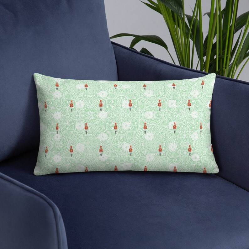 May include: A green throw pillow with a white and red pattern of toy soldiers. The pattern is repeated throughout the pillow.