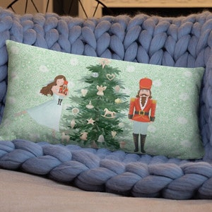 May include: A green Christmas tree with ornaments and a rocking horse, a girl in a blue dress holding a nutcracker, and a nutcracker in a red uniform standing next to the tree. The background is a green and white pattern.