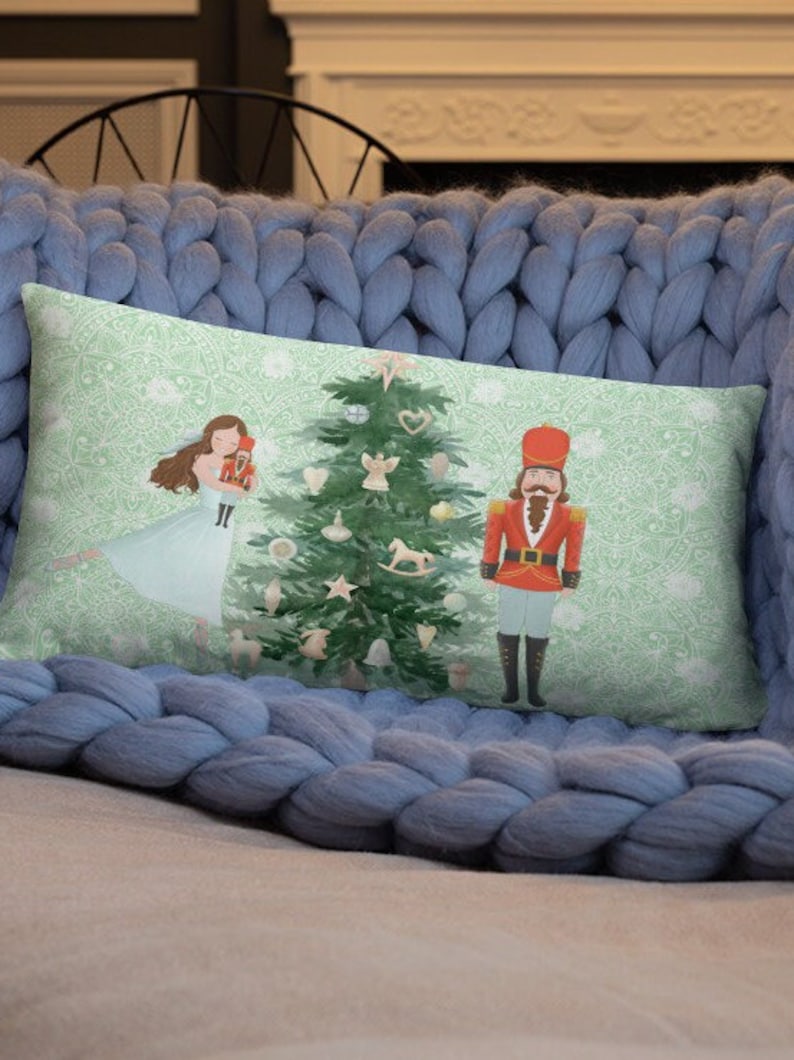 May include: A green Christmas tree with ornaments and a rocking horse, a girl in a blue dress holding a nutcracker, and a nutcracker in a red uniform standing next to the tree. The background is a green and white pattern.