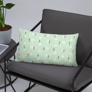 May include: A green and white patterned throw pillow with a repeating design of red toy soldiers. The pillow is on a gray chair.