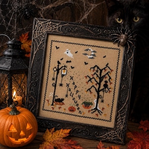 Może przedstawiać: Oprawiony haft krzyżykowy na beżowej tkaninie z napisem Happy Halloween, duchem, księżycem, latarnią uliczną, czarnym kotem, drzewem i dyniami. Czarna ramka jest ozdobiona wzorami pajęczyny i plastikowym pająkiem.