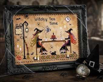 Puede incluir: Un bordado en punto de cruz enmarcado sobre tela beige que muestra a dos brujas en una mesa con el texto Witchy tea time. La escena incluye una tetera, tazas, un pastel, un gato negro, arañas, velas y un letrero de farola con Magic Tea 1692.