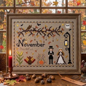 Może przedstawiać: Oprawiony haft krzyżykowy na beżowej tkaninie z napisem November i Thankful, zawierający motywy drzewa, sowy, indyka, dyni, latarni oraz dwóch postaci w strojach historycznych, zamknięty w ozdobnej ramce z motywem obramowania.