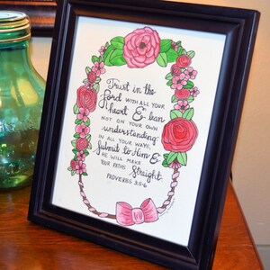 Może przedstawiać: Wydruk w ramie z r&oacute;żowym wieńcem kwiatowym otaczającym ręcznie napisany cytat z Księgi Przysł&oacute;w 3:5-6. Cytat brzmi: "Ufaj Panu z całego serca, a nie polegaj na własnym rozsądku. Na wszystkich swoich drogach uznaj Go, a On prostować będzie twoje ścieżki. Przysł&oacute;w 3:5-6"