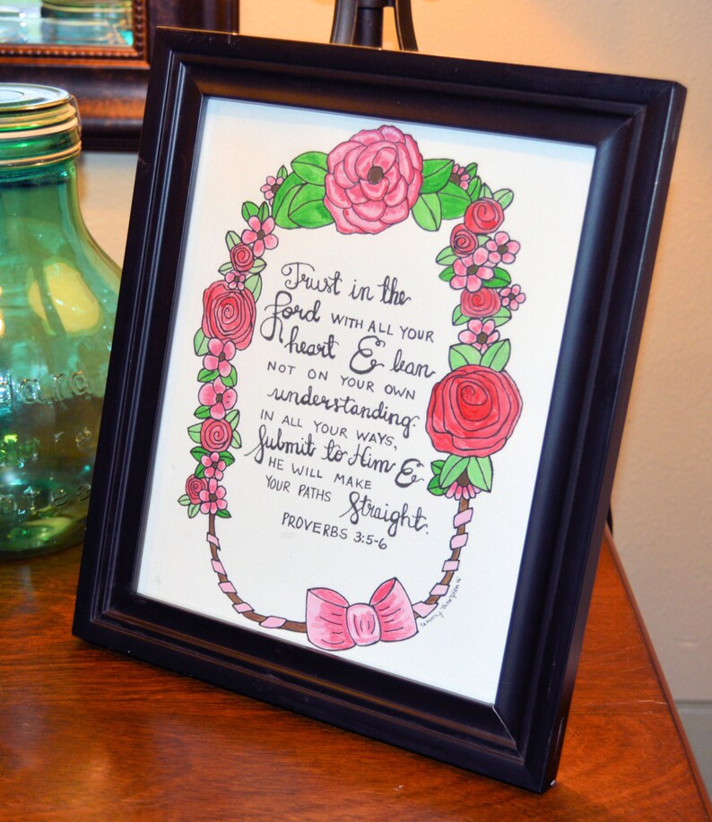 Może przedstawiać: Wydruk w ramie z r&oacute;żowym wieńcem kwiatowym otaczającym ręcznie napisany cytat z Księgi Przysł&oacute;w 3:5-6. Cytat brzmi: "Ufaj Panu z całego serca, a nie polegaj na własnym rozsądku. Na wszystkich swoich drogach uznaj Go, a On prostować będzie twoje ścieżki. Przysł&oacute;w 3:5-6"
