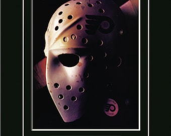 May include: A vintage hockey goalie mask featuring the Philadelphia Flyers logo. The mask is white with black detailing and multiple circular ventilation holes. The image includes a red nameplate with "BERNIE PARENT Philadelphia Flyers 1967-1971 / 1973-1979."