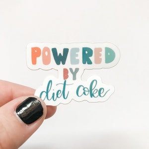 May include: A white sticker with the text "POWERED BY diet coke" in colorful letters. The letters are in a rainbow color scheme of pink, blue, green, and red.