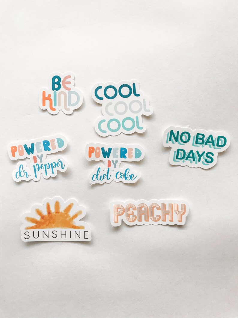 May include: A collection of colorful stickers with positive messages. The stickers include phrases like "Be Kind," "Cool," "Powered by Dr. Pepper," "Powered by Diet Coke," "No Bad Days," "Sunshine," and "Peachy."