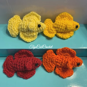 May include: Three crocheted betta fish, one yellow, one orange, and one red. The fish are all in a similar pose with their fins spread out. The fish are all about 3 inches long.