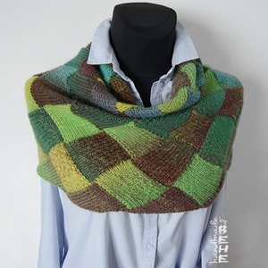 May include: A green, brown and yellow knitted infinity scarf with a chequered pattern. The scarf is handmade by "BEHE".