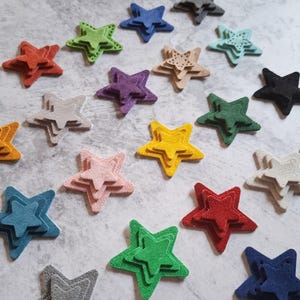 Può includere: Una collezione di decorazioni a forma di stella a strati in vari colori, tra cui rosso, giallo, verde, blu e rosa. Ogni stella ha una superficie strutturata e un effetto tridimensionale, creando un aspetto giocoso e decorativo. Ideali per lavori di artigianato e abbellimento.