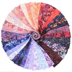 May include: A bundle of 24 fabric squares featuring a floral pattern in shades of purple, pink, and blue. The fabric squares are arranged in a fan shape.