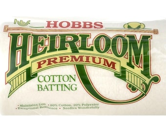 May include: A white package of Hobbs Heirloom Premium Cotton Batting. The package is labeled with green text and a green and yellow logo. The text on the package reads: "Maintains Loft - 80% Cotton, 20% Polyester - Exceptional Resilience - Needles Wonderfully."