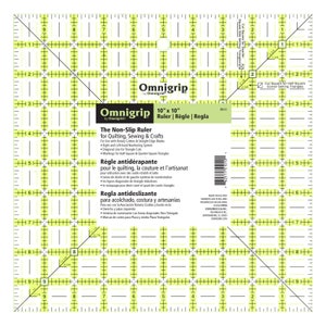 May include: A yellow and white 10-inch by 10-inch Omnigrip non-slip ruler for quilting, sewing, and crafts. The ruler features a grid pattern with markings for half-square and quarter-square triangles. The ruler is made in the USA.