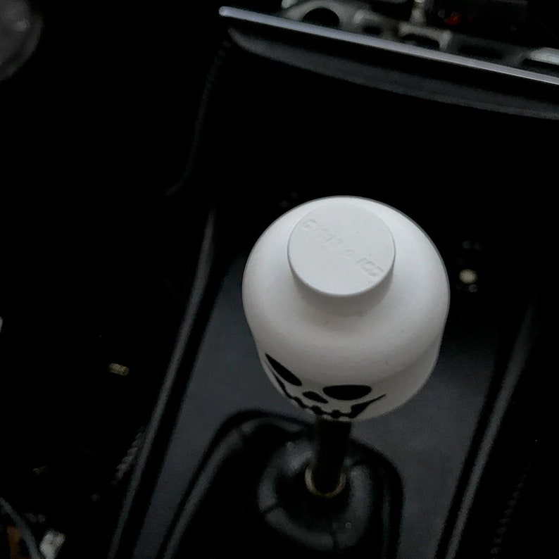 May include: White skull-shaped gear shift knob with a black skull design. The knob has a white top with the word "SHIFTED" printed on it.