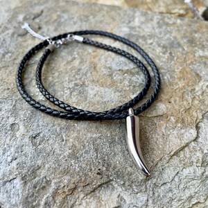 May include: A black leather cord necklace with a silver horn pendant.