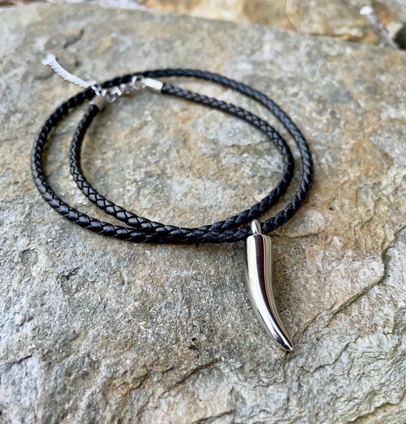 May include: A black leather cord necklace with a silver horn pendant.