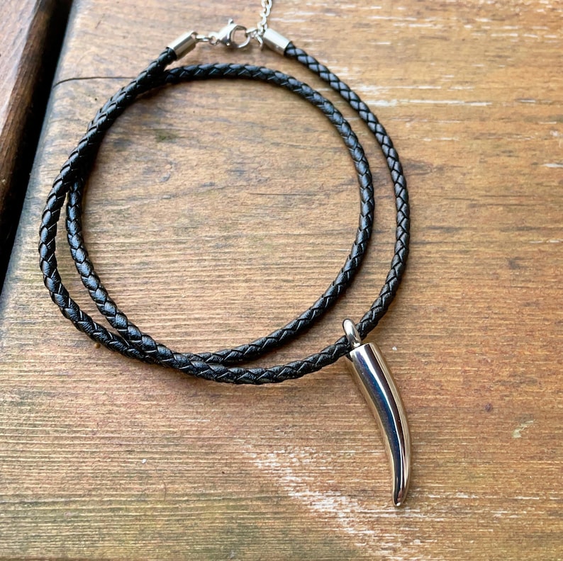 May include: A black leather cord necklace with a silver horn pendant.