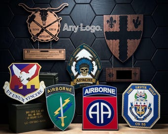 May include: A collection of wooden military-style plaques and emblems featuring various insignias, including the 82nd Airborne, USS Leyte Gulf, and Apache Marine units. The display includes text reading Any Logo and Unmatched Detail and Color.