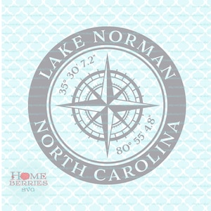 May include: A gray compass with a blue background and the text "LAKE NORMAN 35° 30' 7.2" 80° 55' 4.8" NORTH CAROLINA".