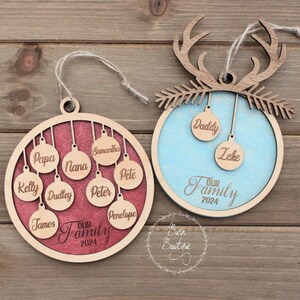 Puede incluir: Dos adornos navideños de madera con fondo rojo y azul. Los adornos están decorados con nombres y el texto "Nuestra familia 2024".