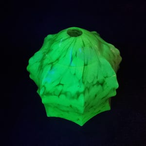 Puede incluir: Una taza de cerámica blanca con asa negra y el texto "But First, Coffee" en negrita negra. La taza se encuentra sobre un fondo borroso, sugiriendo un ambiente acogedor.